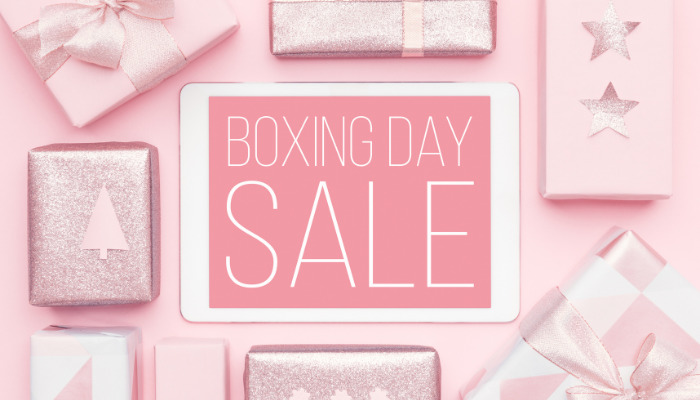 A pink image of pink presents all strewn around the edges with a white ipad in the middle showing the text boxing day sale.